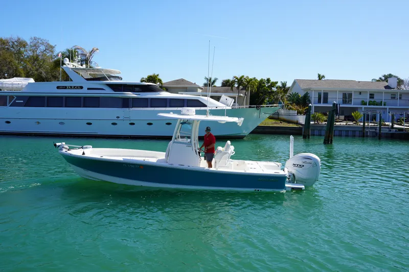  Yacht Photos Pics 2024 Regulator 26XO boat cruising in a sunny marina with luxury yachts and waterfront homes.