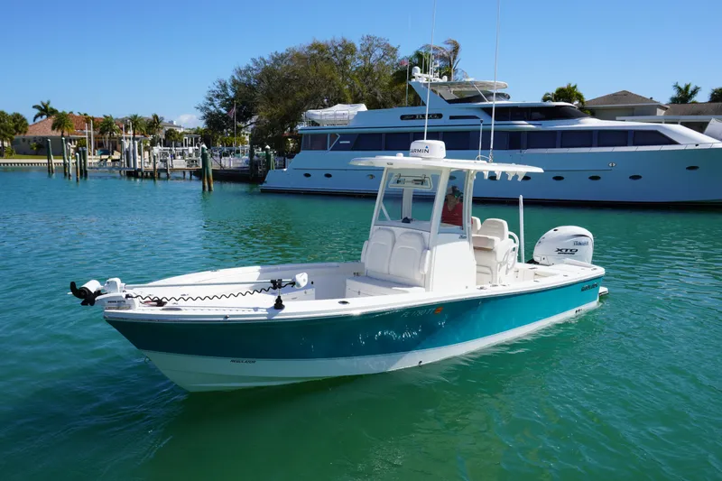  Yacht Photos Pics 2024 Regulator 26XO boat on turquoise water, docked near luxury yacht.