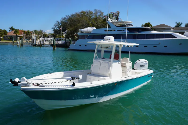  Yacht Photos Pics 2024 Regulator 26XO boat on turquoise water near a marina and luxury yacht.