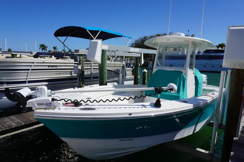  Yacht Photos Pics 2024 Regulator 26XO boat docked with Minn Kota trolling motor, turquoise cover, and sunny marina backdrop.