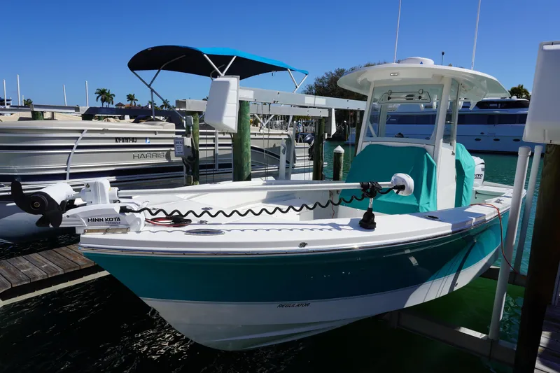  Yacht Photos Pics 2024 Regulator 26XO boat docked, featuring Minn Kota trolling motor, turquoise accents, and sunny marina setting.
