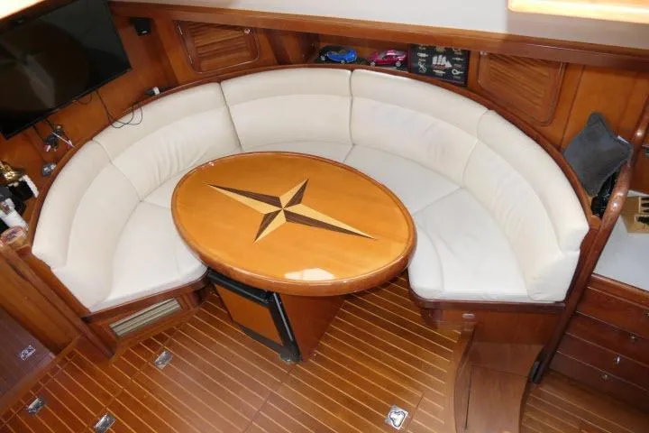 Majestic Yacht Photos Pics Luxurious 2006 Tayana 58 Deck Salon interior with elegant wood finish and curved seating.