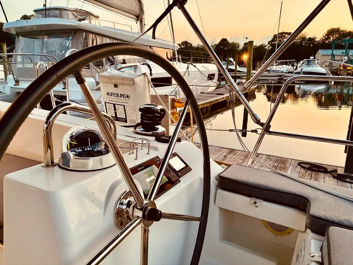  Yacht Photos Pics 2017 Beneteau Oceanis 45 sailboat cockpit at sunset, featuring steering wheel and navigation instruments.