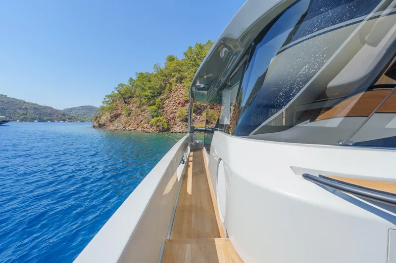 Mama Punch Yacht Photos Pics 2021 Bluegame BGX70 yacht cruising near a scenic coastline with clear blue water.