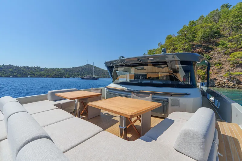 Mama Punch Yacht Photos Pics Luxury Bluegame BGX70 yacht deck with seating and tables, surrounded by scenic water and greenery.