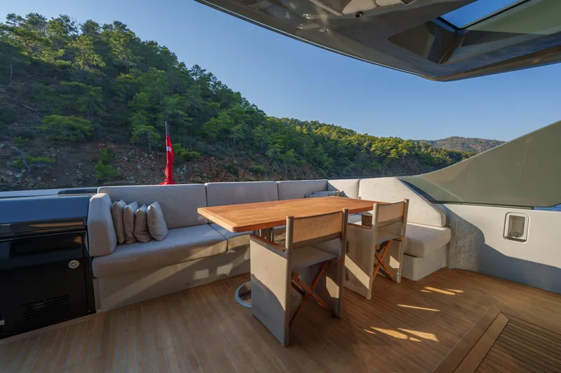 Mama Punch Yacht Photos Pics Outdoor seating area on 2021 Bluegame BGX70 yacht with scenic forest view.