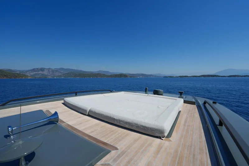Mama Punch Yacht Photos Pics Luxury deck of 2021 Bluegame BGX70 yacht with sunbed, overlooking serene ocean view.