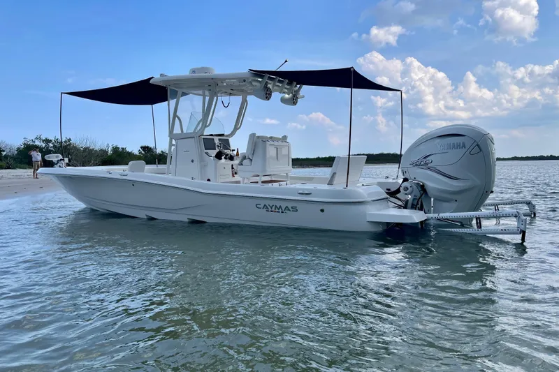  Yacht Photos Pics 2020 Caymas 28 HB boat with Yamaha engine, anchored near a sandy shore under a blue sky.