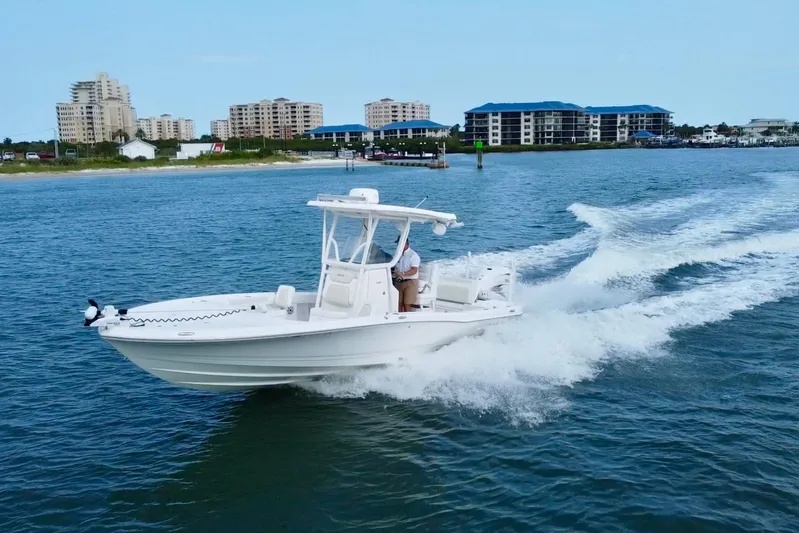  Yacht Photos Pics 2020 Caymas 28 HB boat cruising on water near coastal buildings.