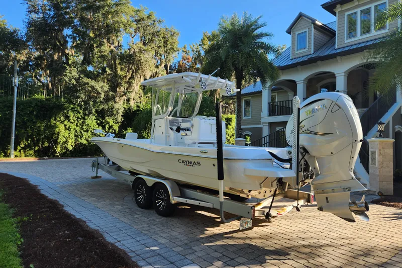  Yacht Photos Pics 2020 Caymas 28 HB boat on trailer in driveway, surrounded by lush greenery.