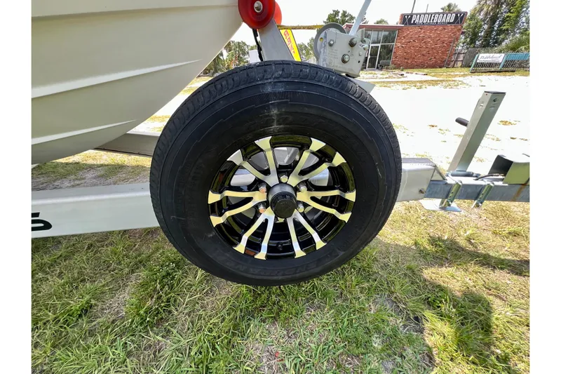  Yacht Photos Pics Trailer wheel of 2020 Caymas 28 HB boat on grassy area.