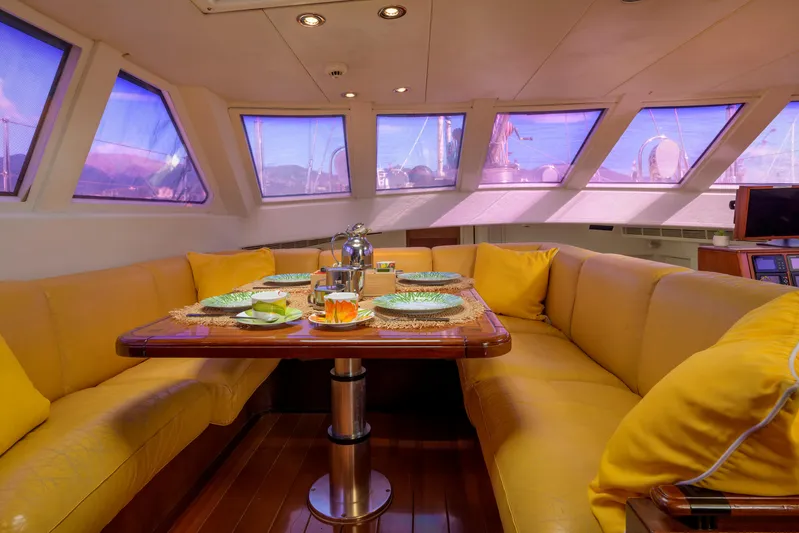 Billy Budd II Yacht Photos Pics Luxurious yacht interior with yellow seating, dining table set, and panoramic windows. Royal Huisman 112' Custom, 1994.