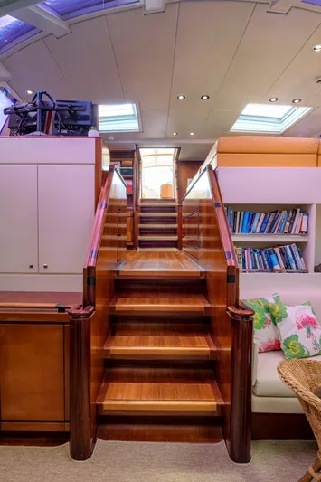 Billy Budd II Yacht Photos Pics Luxurious wooden staircase inside 1994 Royal Huisman 112' Custom yacht, featuring bookshelves and skylights.