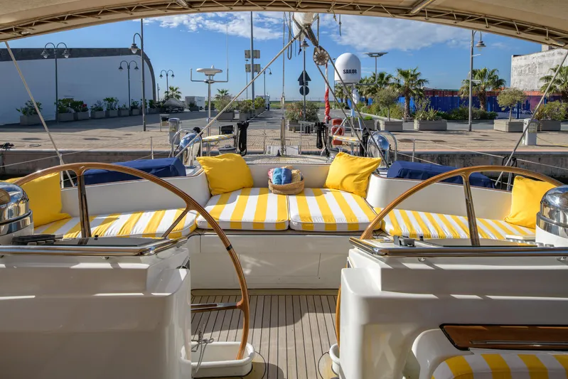 Billy Budd II Yacht Photos Pics Luxurious Royal Huisman 112' Custom yacht deck with striped seating, yellow cushions, and dual steering wheels.