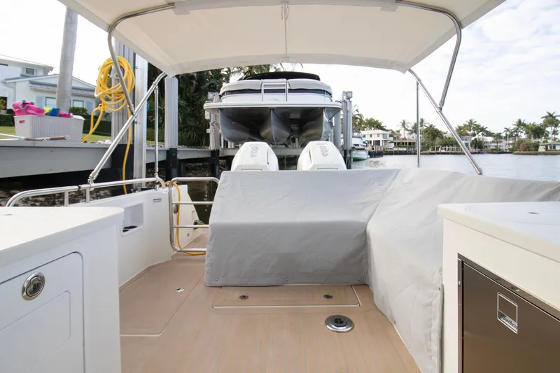  Yacht Photos Pics 2025 MJM 38 X boat interior with covered seating, docked by waterfront homes.