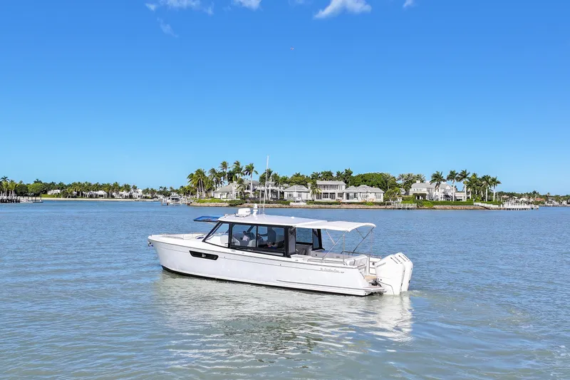  Yacht Photos Pics 2025 MJM 38 X boat cruising on a sunny day near waterfront homes.