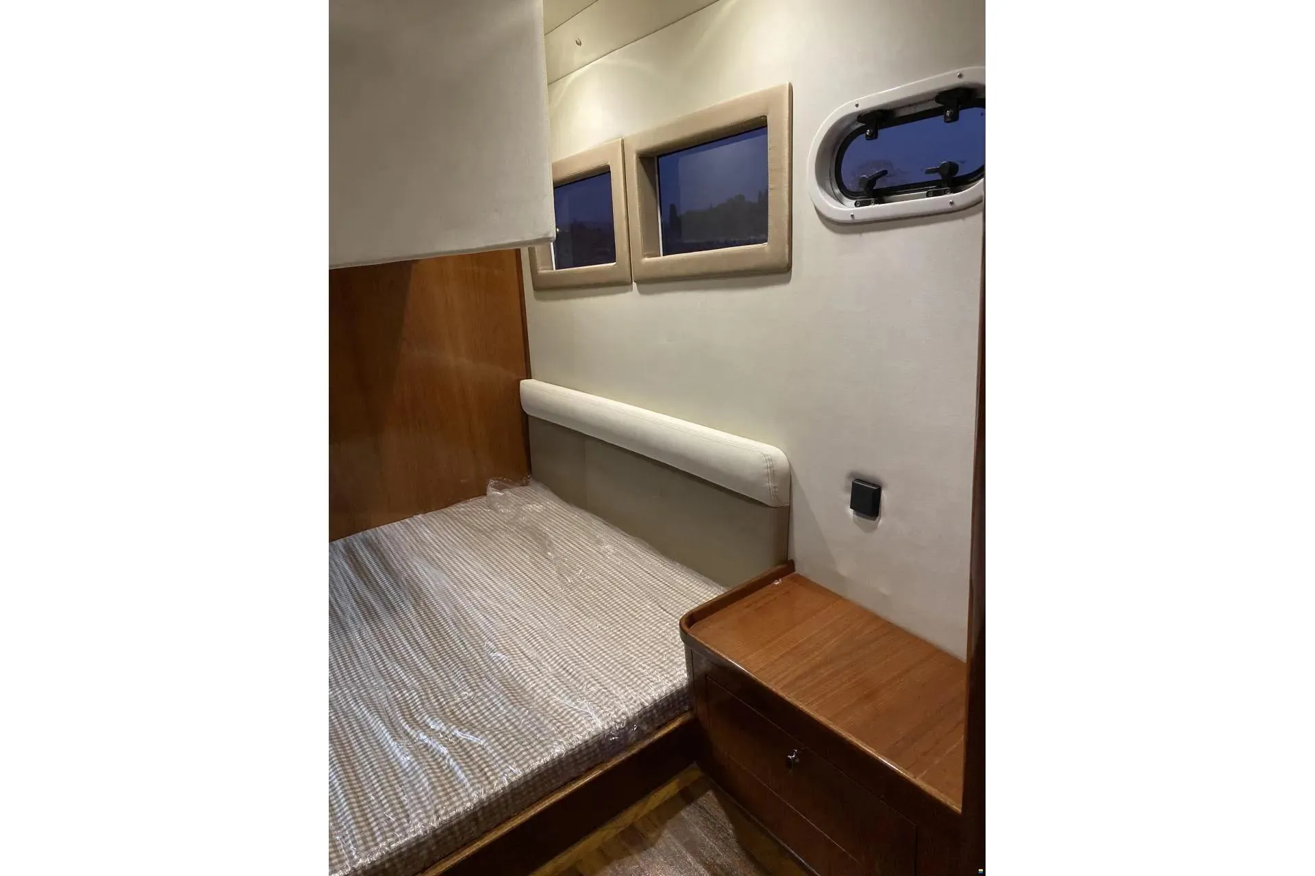 Cozy cabin interior of Erman Yachting Comfort 36 with wooden furnishings and porthole windows.