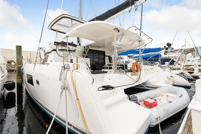 Aquaholic Yacht Photos Pics 2018 Lagoon 42 catamaran docked with dinghy, white hull, and spacious deck.