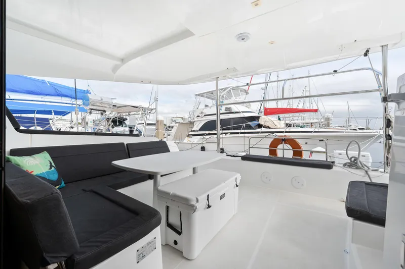 Aquaholic Yacht Photos Pics Spacious deck of 2018 Lagoon 42 catamaran with seating and table, docked at marina.