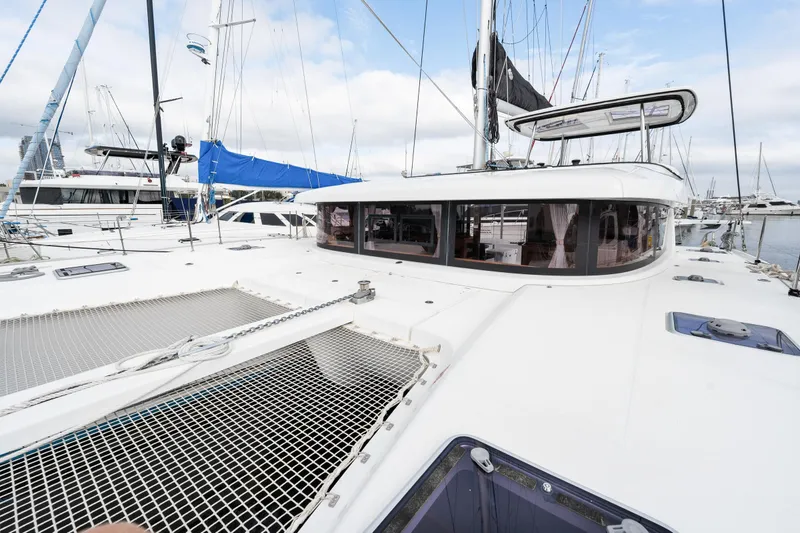 Aquaholic Yacht Photos Pics 2018 Lagoon 42 catamaran docked at a marina, showcasing its spacious deck and netting.