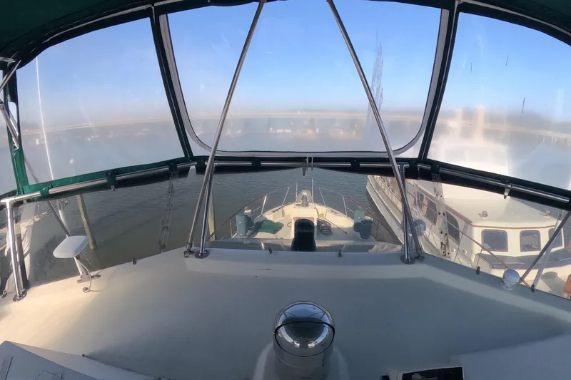 Saint Paul Yacht Photos Pics 1987 Hatteras 54 Motor Yacht helm view with clear canopy and marina backdrop.
