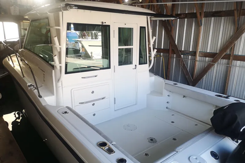  Yacht Photos Pics 2016 Boston Whaler 315 Conquest Pilothouse in a boat shed, showcasing spacious deck.