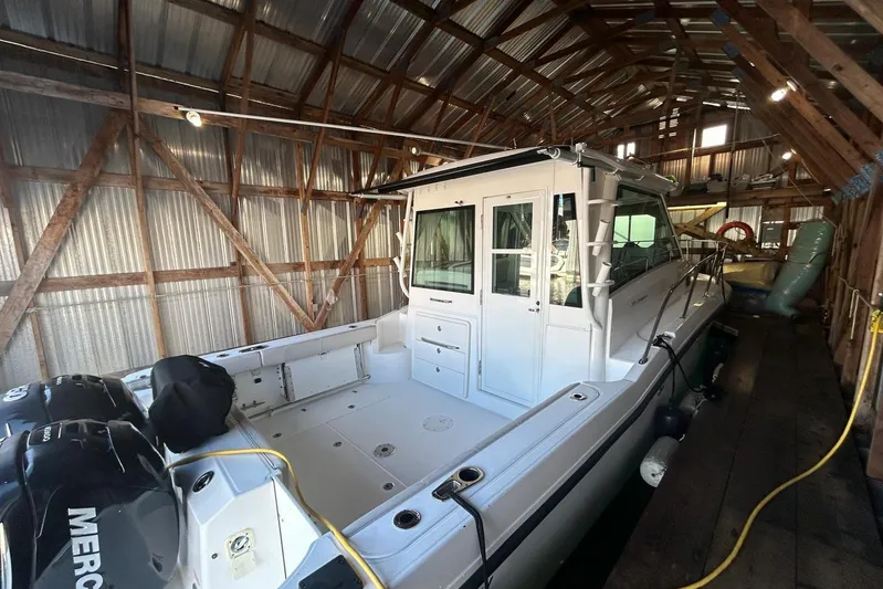 Yacht Photos Pics 2016 Boston Whaler 315 Conquest Pilothouse in wooden boathouse, showcasing spacious deck and twin engines.