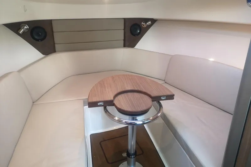  Yacht Photos Pics 2016 Boston Whaler 315 Conquest Pilothouse interior with cushioned seating and wooden table.
