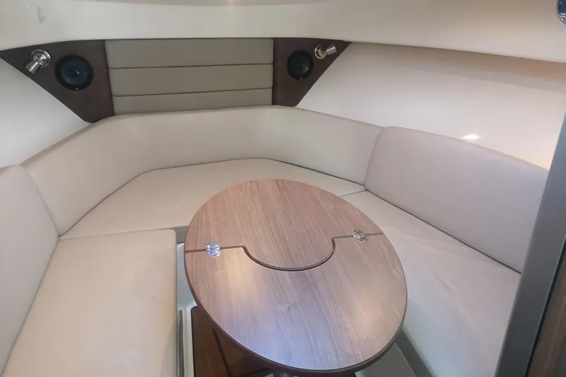  Yacht Photos Pics 2016 Boston Whaler 315 Conquest Pilothouse interior with cushioned seating and wooden table.