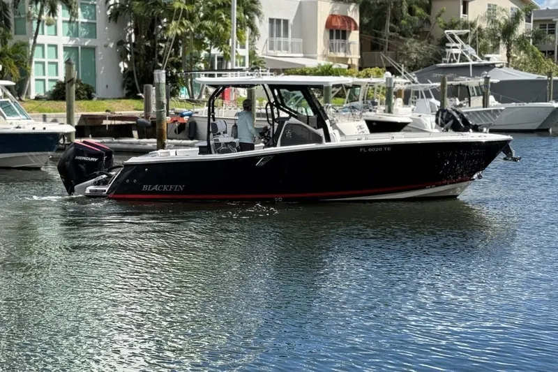  Yacht Photos Pics 2022 Blackfin 272 CC boat cruising in a marina with waterfront buildings.