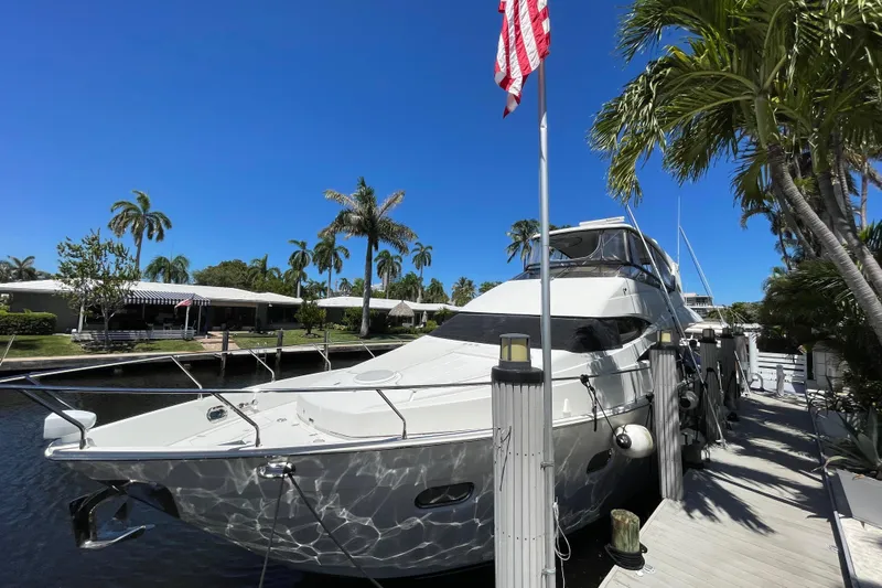  Yacht Photos Pics Luxury 2006 Marquis 59 yacht docked by palm trees under clear blue sky.