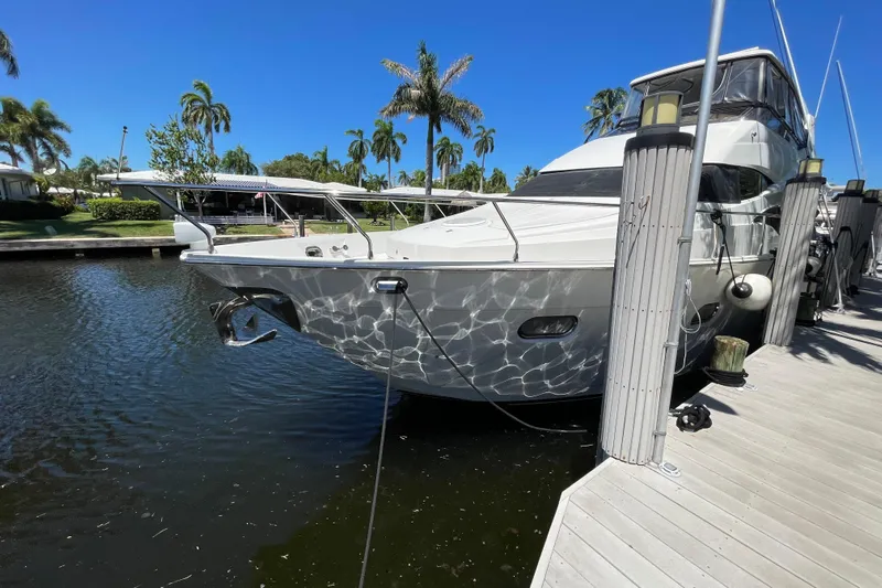  Yacht Photos Pics Luxury 2006 Marquis 59 yacht docked, surrounded by palm trees and clear blue sky.