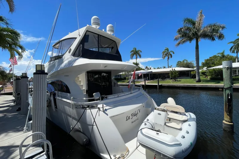  Yacht Photos Pics Luxury 2006 Marquis 59 yacht docked by palm trees under clear blue sky.