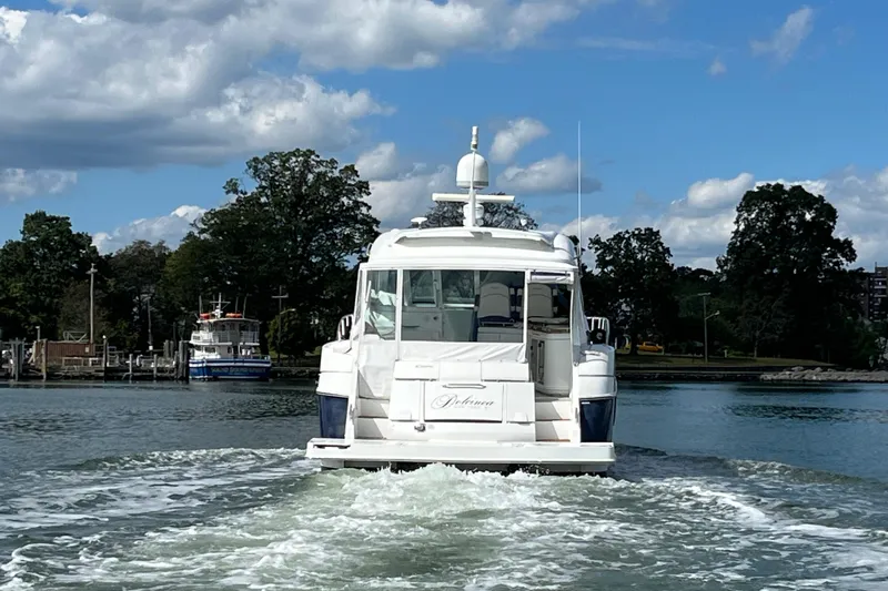 Dolcinea Yacht Photos Pics 2010 Cruisers Yachts 520 Sports Coupe on water, surrounded by trees and blue sky.
