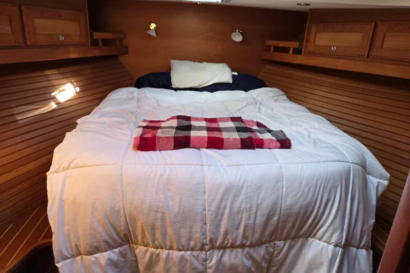 Grayson Yacht Photos Pics Cozy bedroom in 2017 Sabre 48 Fly Bridge yacht with wooden paneling and plaid blanket.