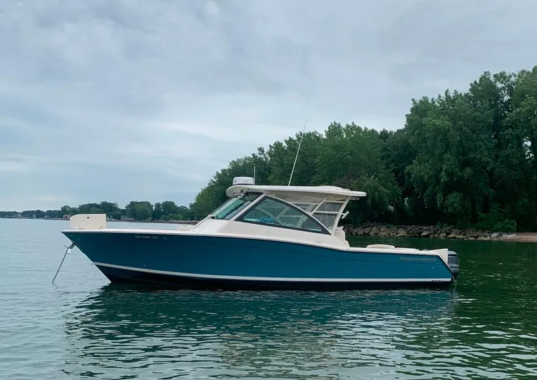  Yacht Photos Pics 2019 Grady-White Freedom 375 boat on calm water near a wooded shoreline.