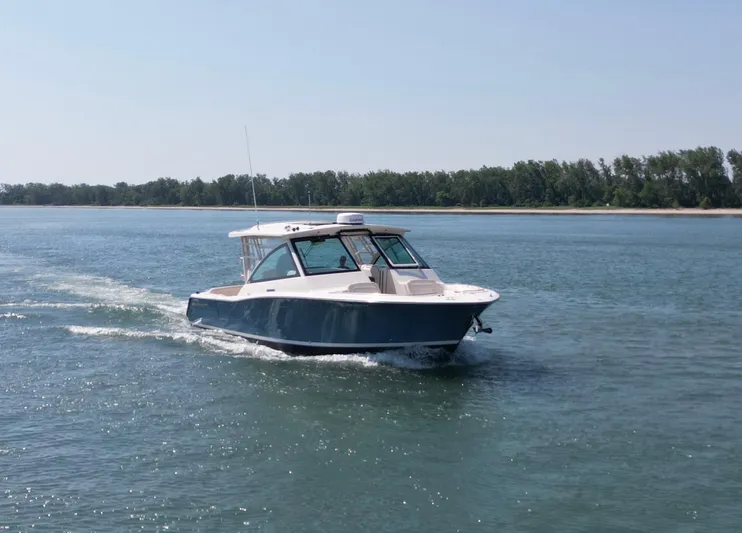 Yacht Photos Pics 2019 Grady-White Freedom 375 boat cruising on a calm lake with forested shoreline.