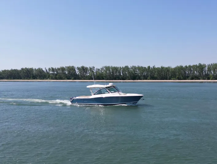  Yacht Photos Pics 2019 Grady-White Freedom 375 boat cruising on a calm lake with a forested shoreline.