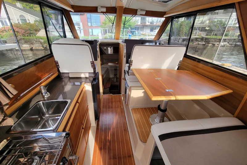  Yacht Photos Pics 2017 Cutwater C28 boat interior with wooden finishes, dining table, and kitchenette.
