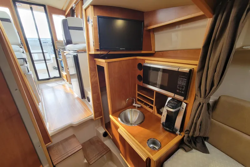  Yacht Photos Pics Interior of 2017 Cutwater C28 boat with kitchenette, TV, and seating area.