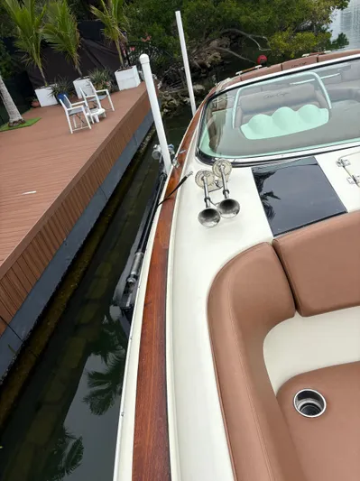  Yacht Photos Pics 2015 Chris-Craft Launch 32 docked near a wooden deck with outdoor seating.