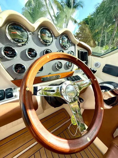 Yacht Photos Pics 2015 Chris-Craft Launch 32 dashboard with wooden steering wheel and gauges, surrounded by palm trees.