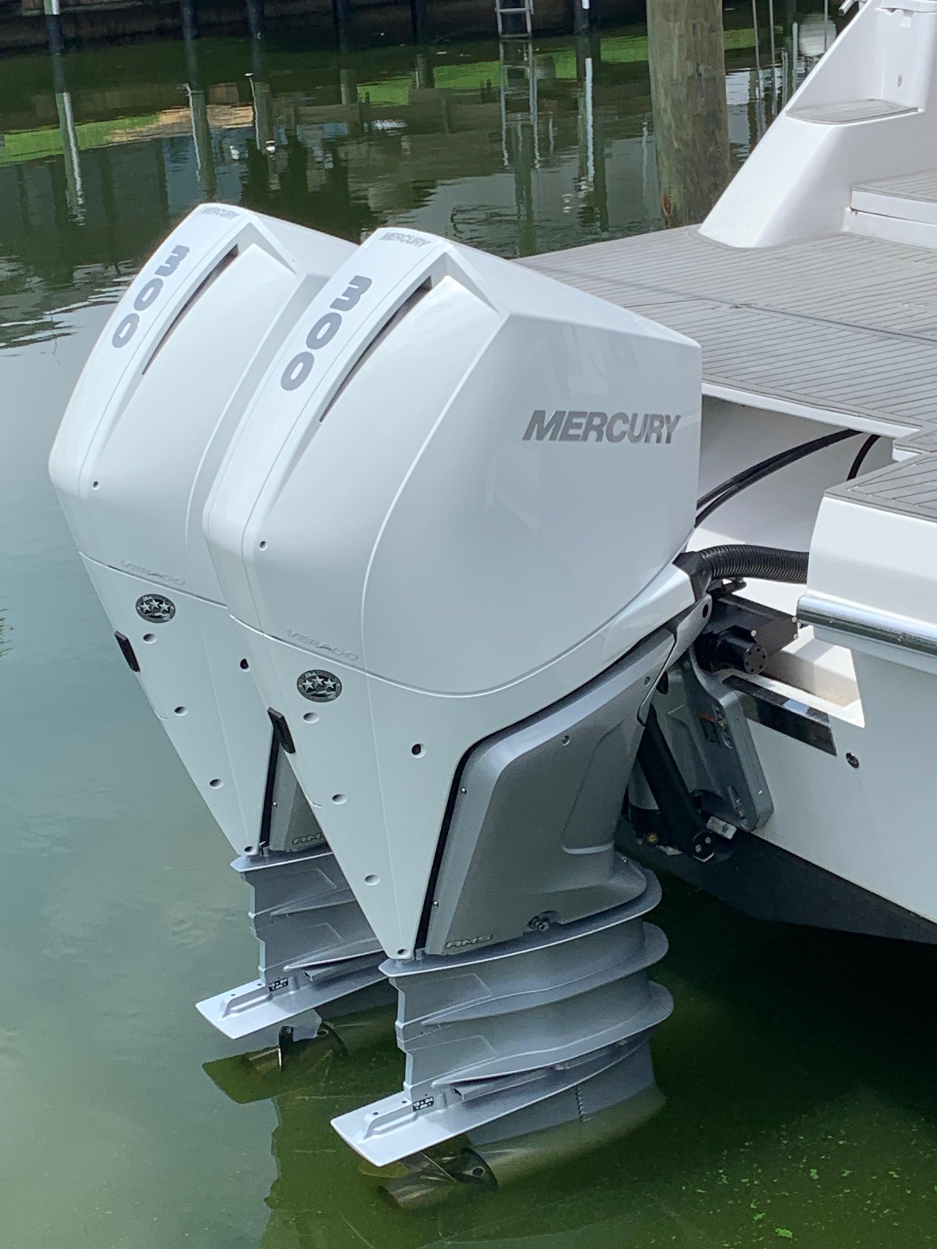 Twin Mercury outboard motors on a 2022 Evolve 360HT boat, docked in calm water.