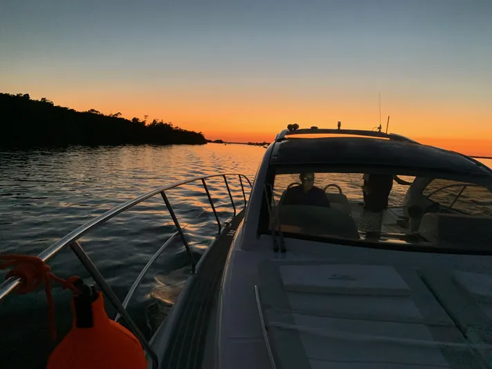  Yacht Photos Pics Evolve 360HT yacht cruising at sunset, 2022 model, serene water and vibrant sky.