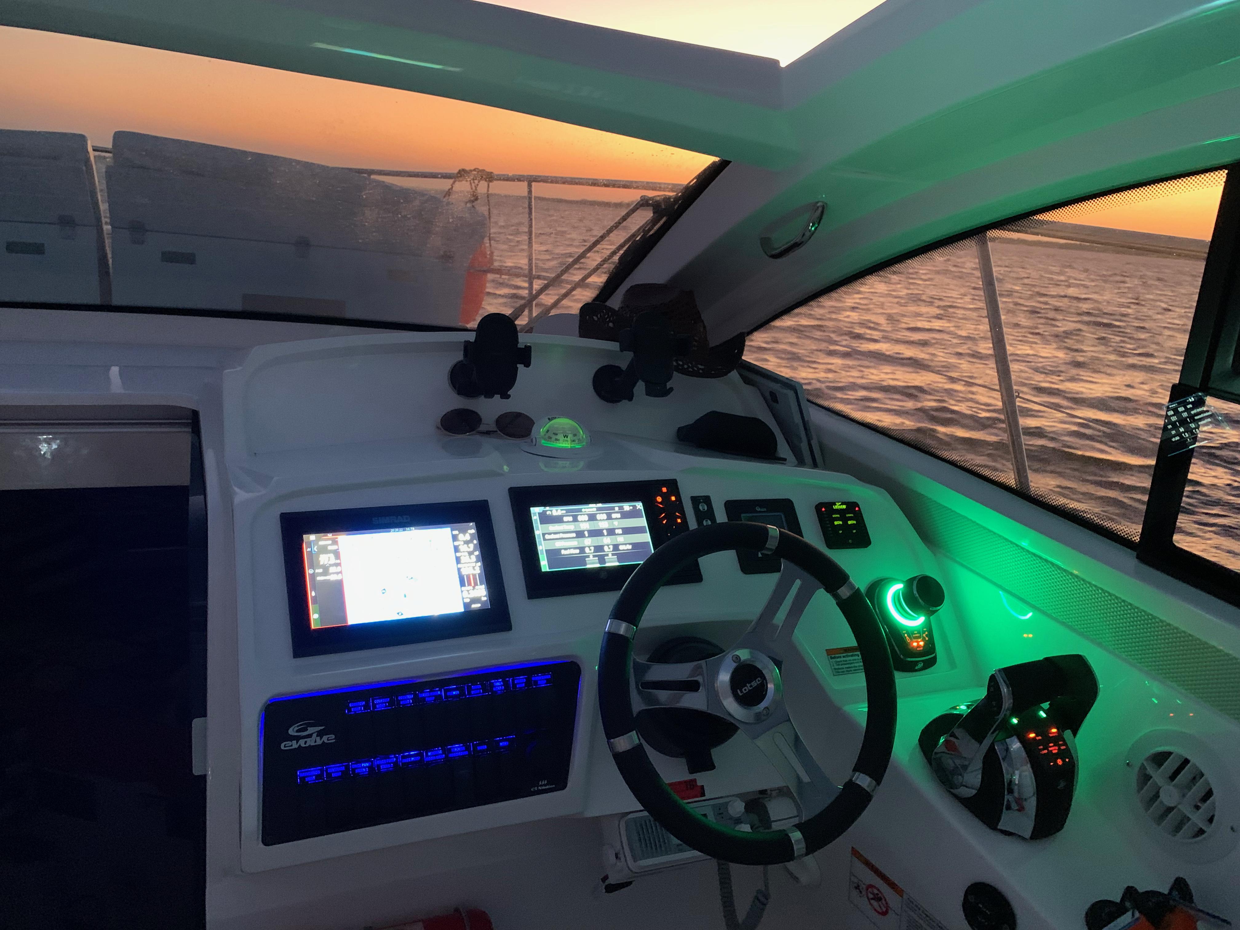 Helm of 2022 Evolve 360HT boat at sunset, featuring modern navigation equipment.