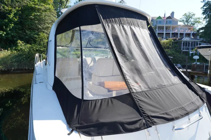  Yacht Photos Pics 2010 Sea Ray 370 Sundancer with black canvas cover docked near lush greenery.