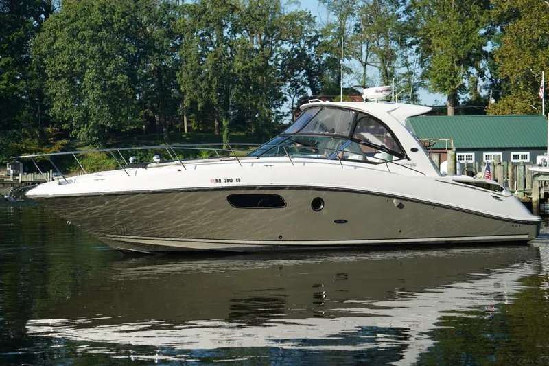  Yacht Photos Pics 2010 Sea Ray 370 Sundancer yacht on calm water, surrounded by lush greenery.