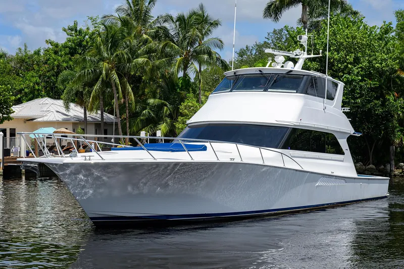  Yacht Photos Pics 2001 Viking 65 Enclosed Bridge yacht on a serene waterway, surrounded by lush greenery.