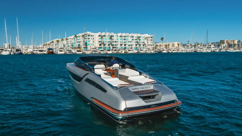 Mrs. Nicely Yacht Photos Pics 2020 Riva Dolceriva yacht cruising in a marina with modern buildings in the background.