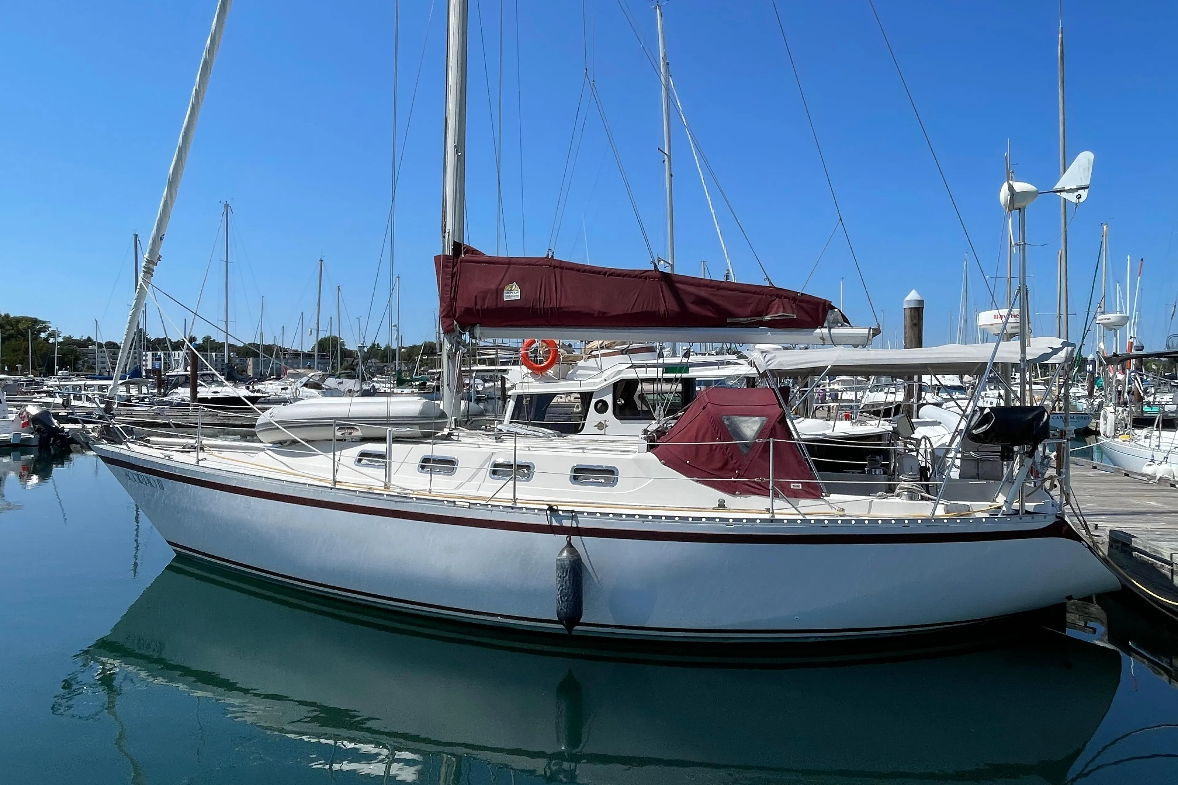 1980 CS 36 Traditional sailboat docked in marina, clear blue sky, calm water.